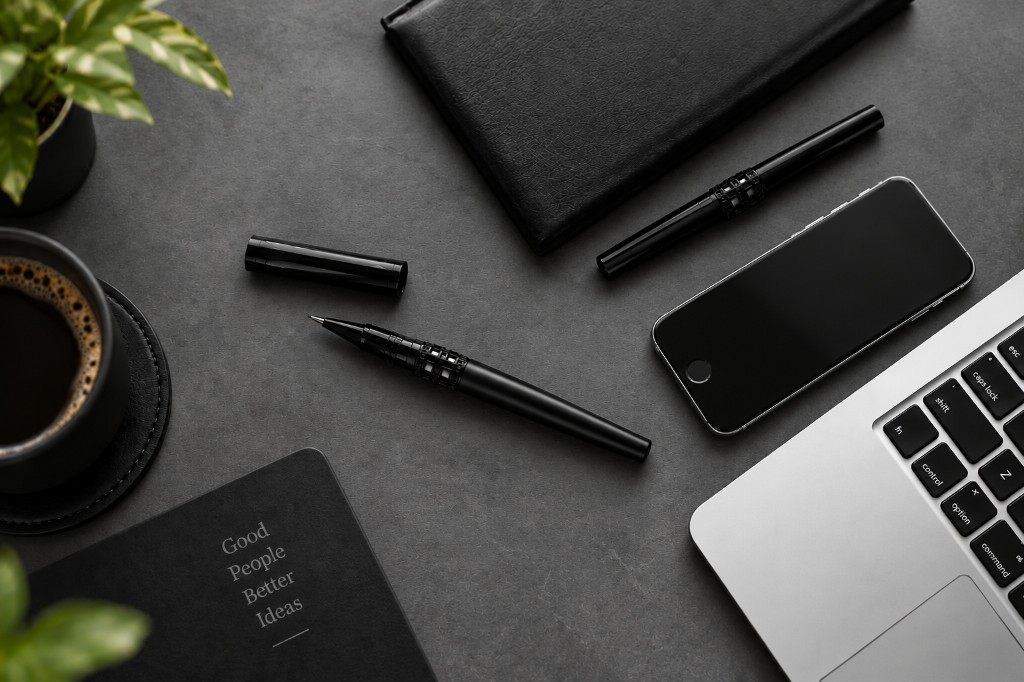 Infinity Cut pens on a dark desk with laptop and coffee